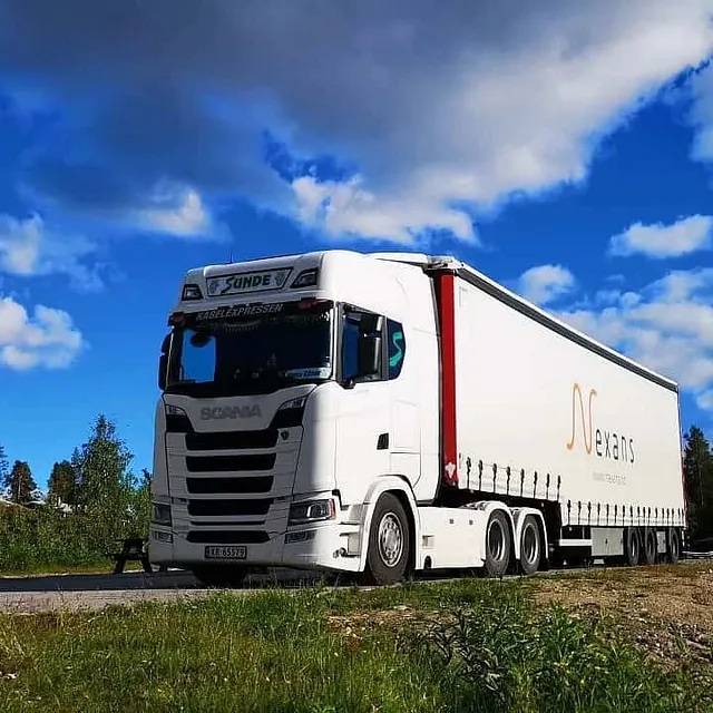 Vogntog parkert ved rasteplass i skogsområde under blå himmel med spredte skyer.