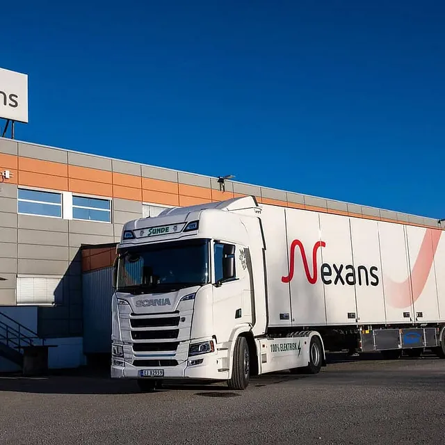 Elektrisk lastebil står ved lasteområde utenfor Nexans-fabrikken under klar blå himmel.